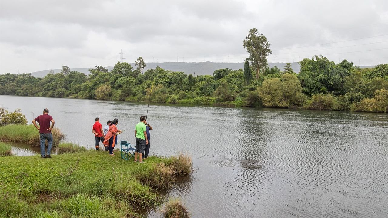 Guests at Forest Escapes Koyna enjoy the view of a river or lake from the shore.