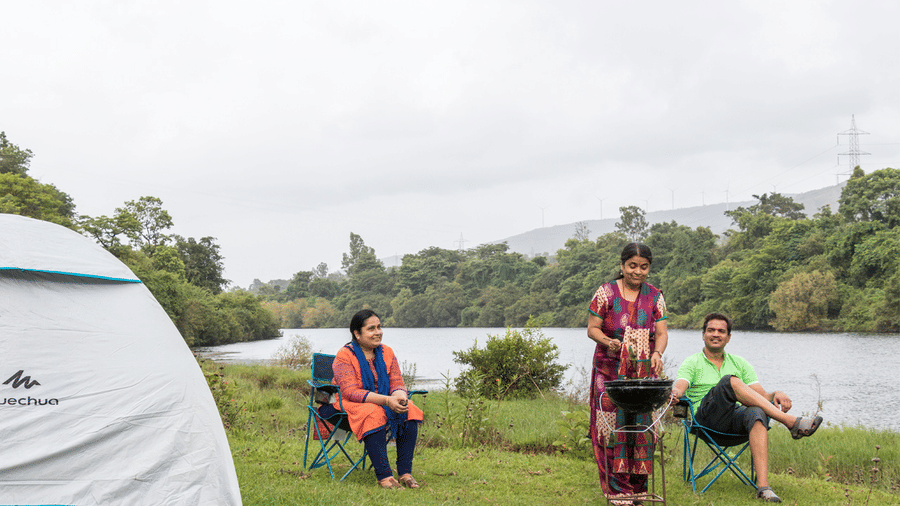 Camping at Forest Escapes Koyna with tents pitched near a scenic water body.