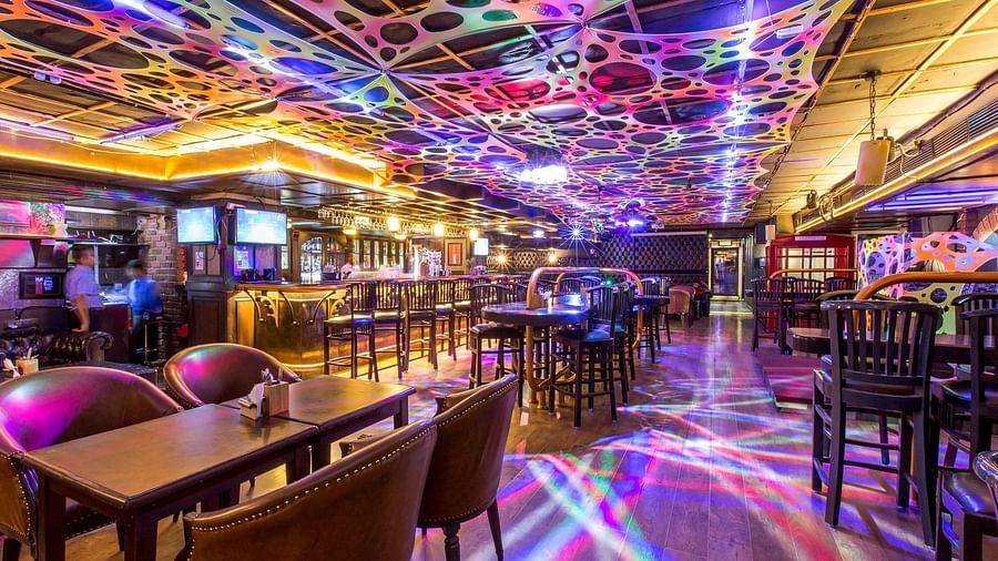 Indoor nightclub scene with vibrant lighting, a bar counter, and people enjoying the nightlife atmosphere.