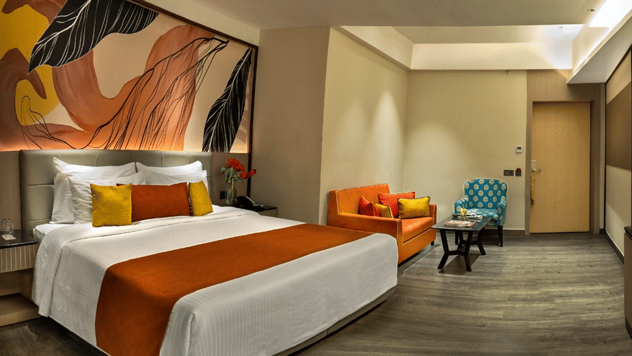 Elegant bedroom with king bed, accent artwork and seating area at The Sonnet, Jamshedpur.