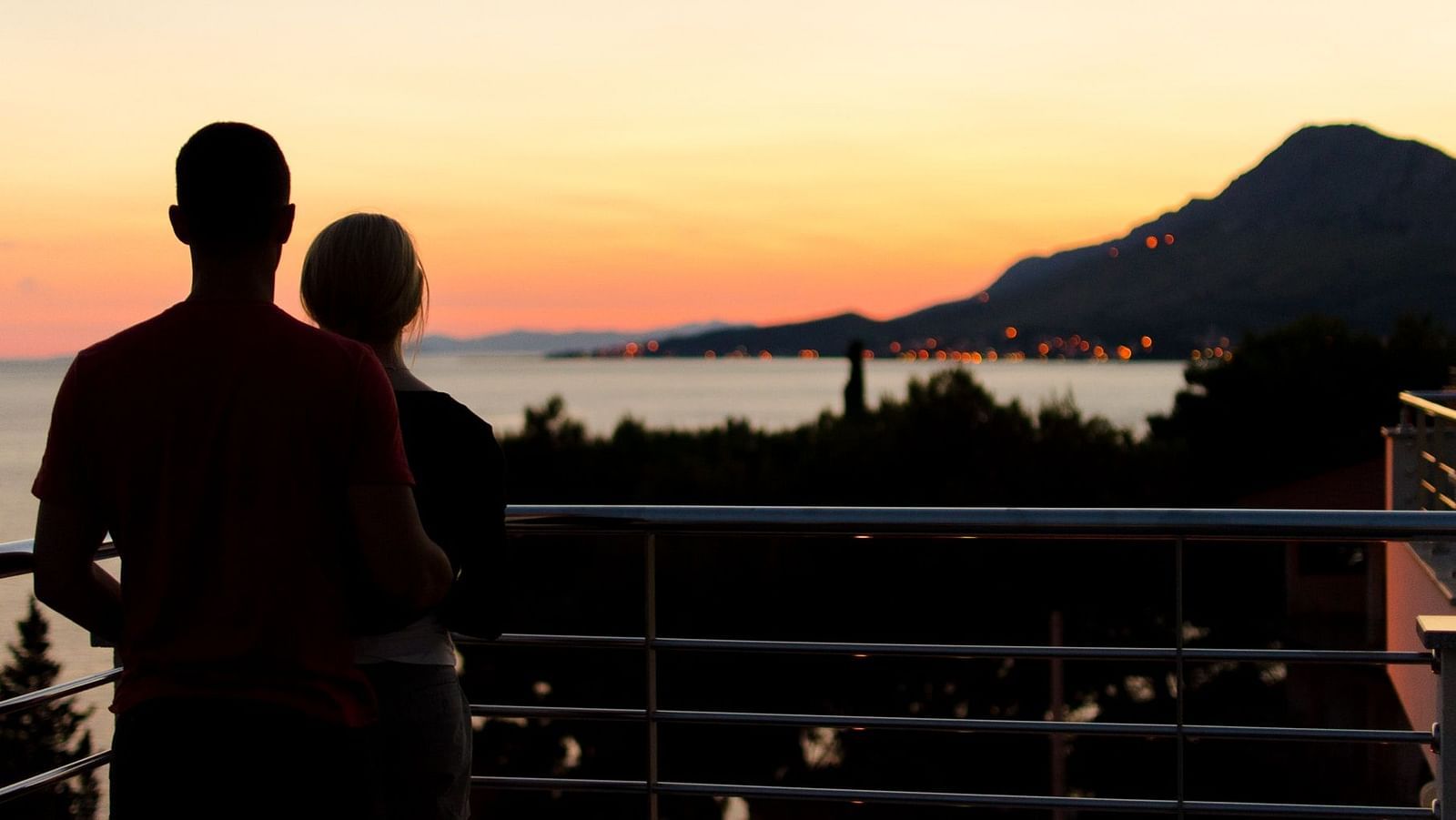 An image showcasing a stunning view of the sea from the balcony of a luxurious room with a couple standing near the balcony 