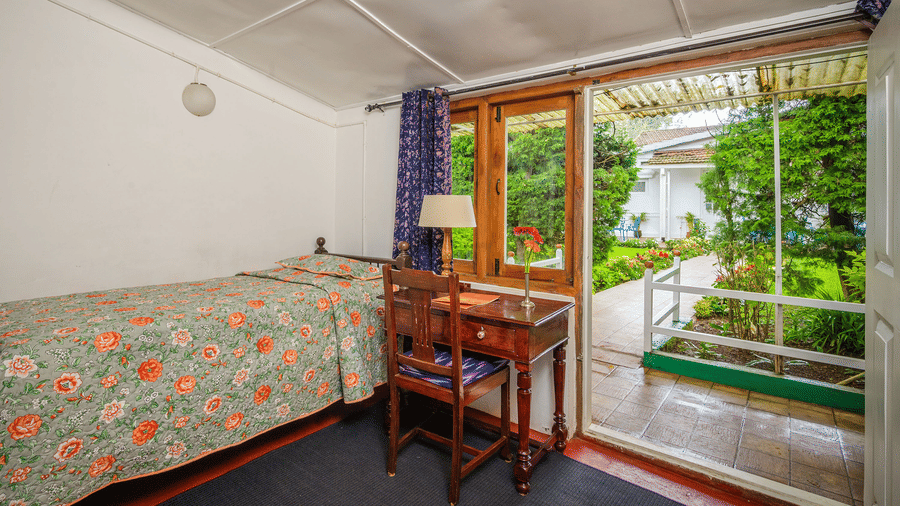 Silver Oak bedroom at Wallwood Garden - 19th Century, Coonoor showing a single bed, writing desk and direct access to the garden.
