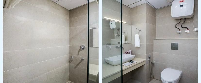 A hotel bathroom with a shower stall on the left, and a toilet and sink on the right | DLS La Serene Manali