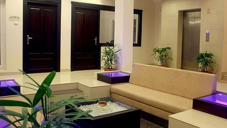A picture showing a corner sofa in the middle of  a room, near a pillar, beside two doors, in calm lights