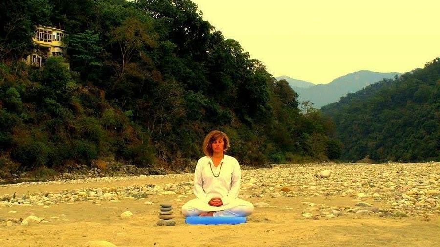 a woman performing yoga aasan in front of a valley