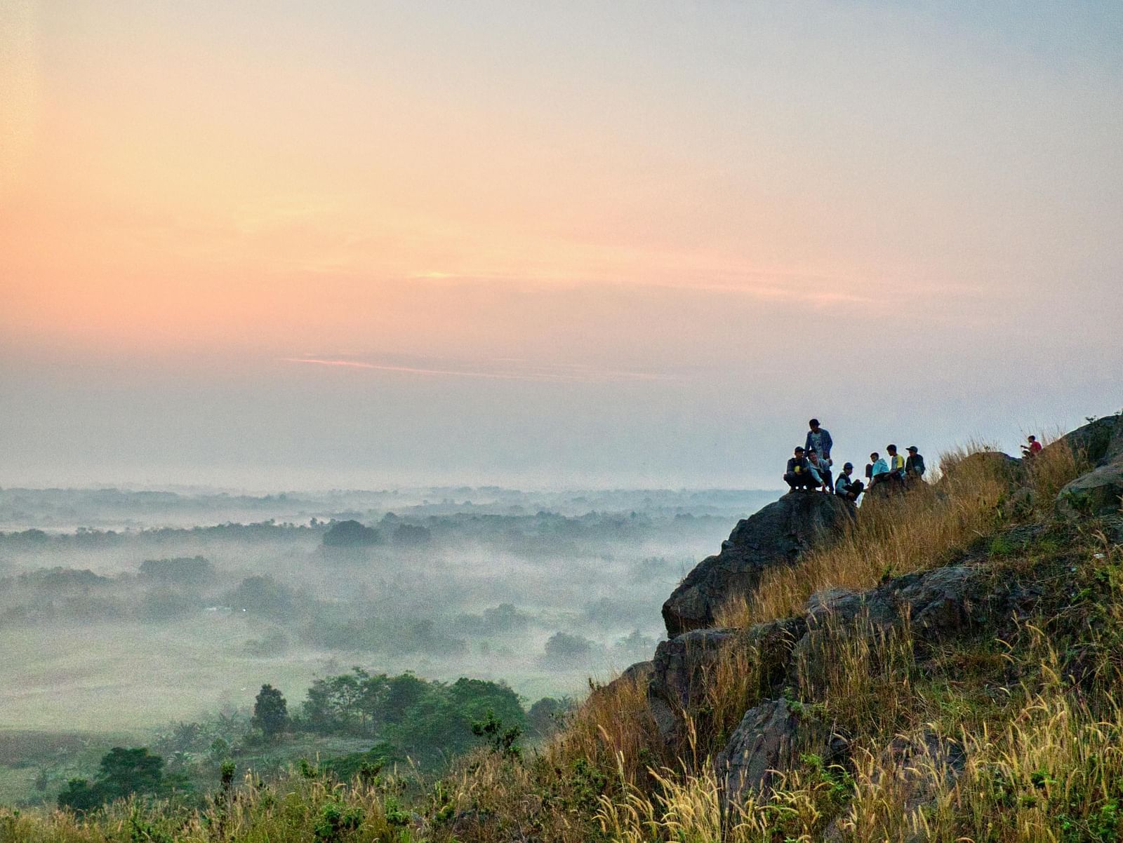 An image of a group of people sitting on a mountain top enjoying the scenic view