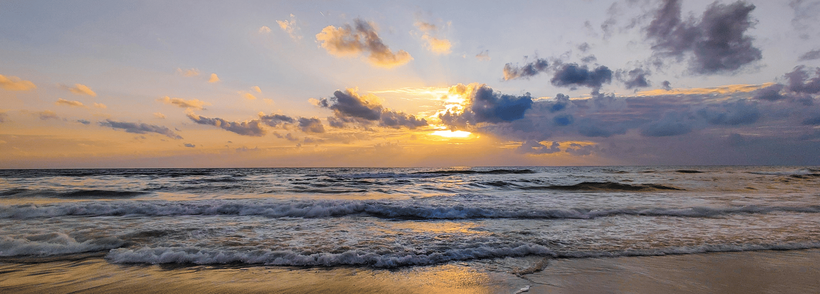 A serene sunset at the beach, with vibrant colours reflecting on the water near The Raintree, St. Mary's Road