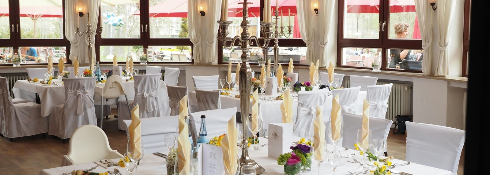 A large event space or banquet hall set up with multiple round tables covered in white tablecloths and decorated for a formal occasion.