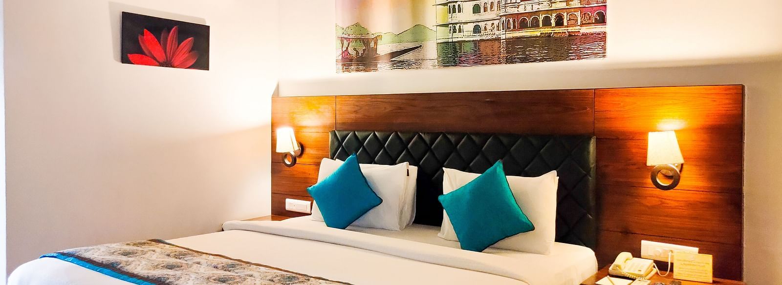 A spacious hotel room with a large bed, accent pillows, and a patterned runner. - Bamboo Saa Resort & Spa, Udaipur