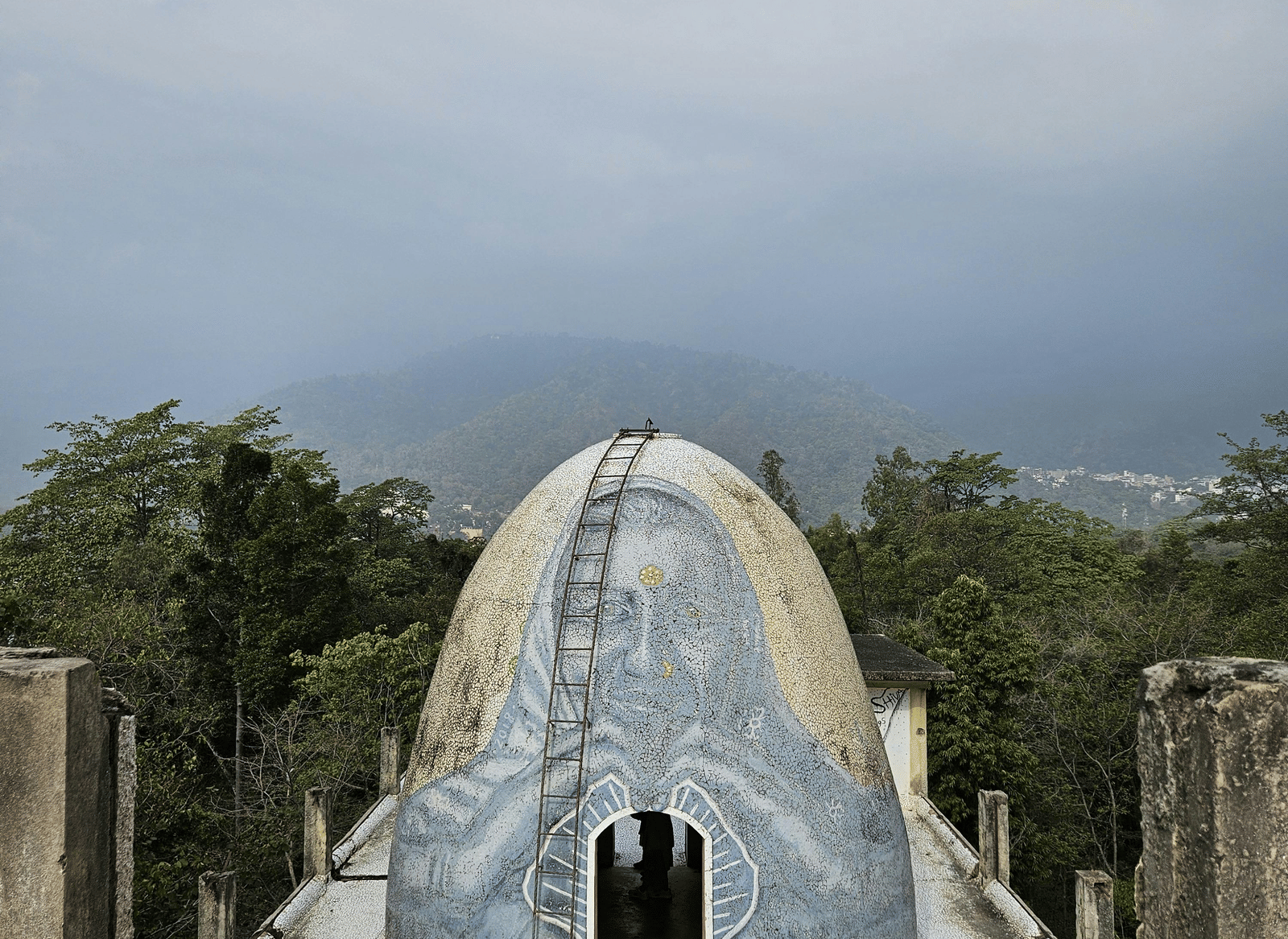 A long, paved walkway or path leading toward a dome like structure, with trees lining the sides
