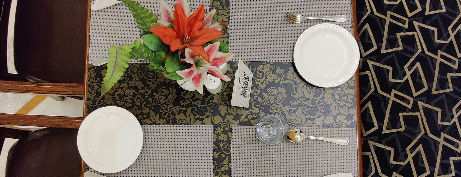 Top angle shot of the dining table at Gold Plate with a small flower vase kept on the table - Hotel Gold, Panipat