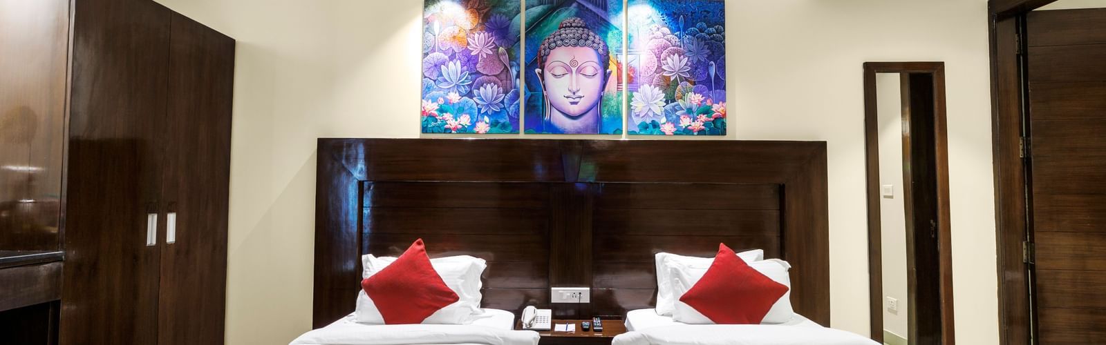 Room with twin beds, dark wood headboards, wardrobe, and framed artwork above the beds at Inde Reva Resorts Rishhikesh .