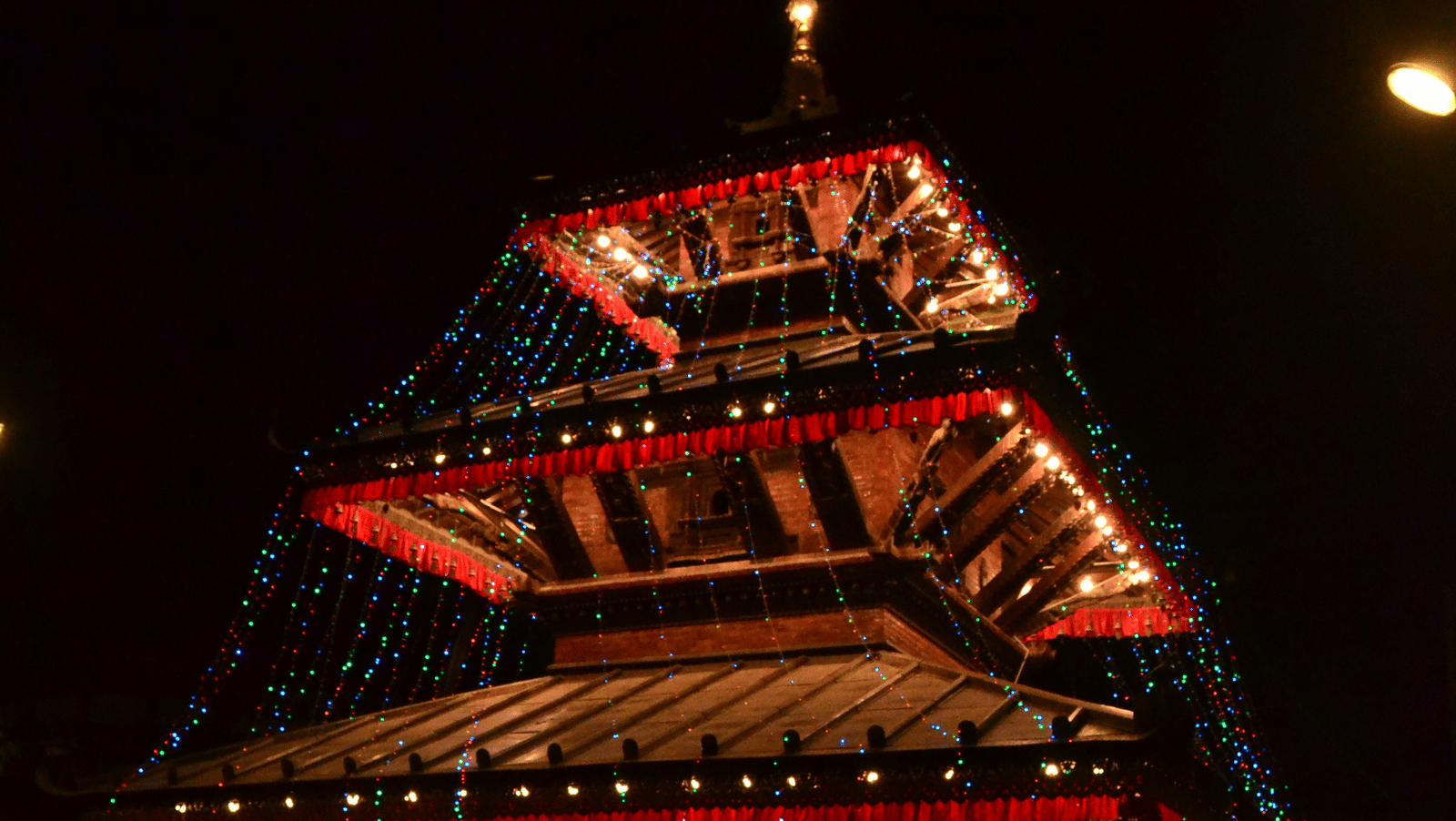 A tall, pagoda-style temple or tower illuminated brightly at night against a dark sky.