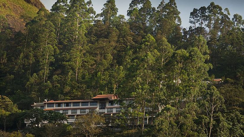 Abad Copper Castle building nestled among lush green trees on a hillside.