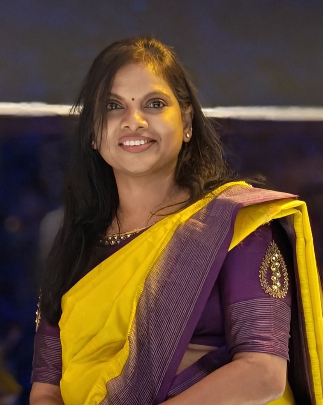 An image of Ms. Uma Maheswari - Senior General Manager - Radisson Hotel Bengaluru City Center where she is half sitting on a high  table