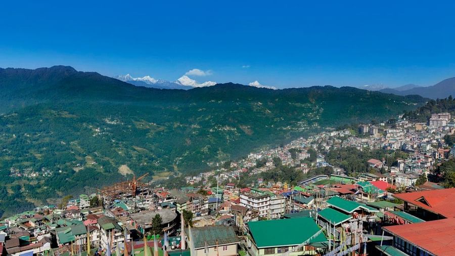 An image of a town with the backdrop of mountains and blue sky which is also the view from Yashshree Sikkim Blossom, Gangtok