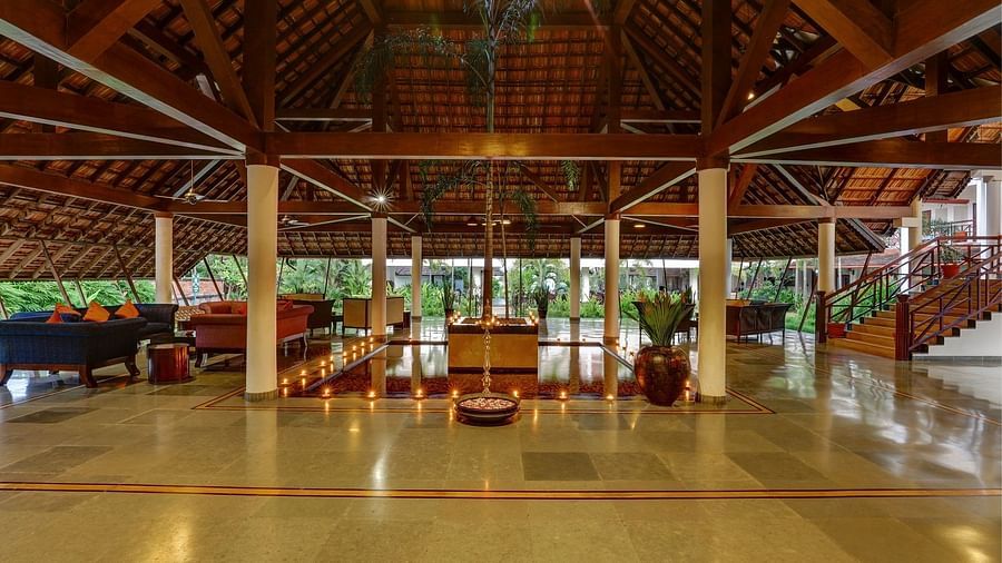 Lobby with flowers in a golden vessel and wooden roof structure - Rhythm Kumarakom