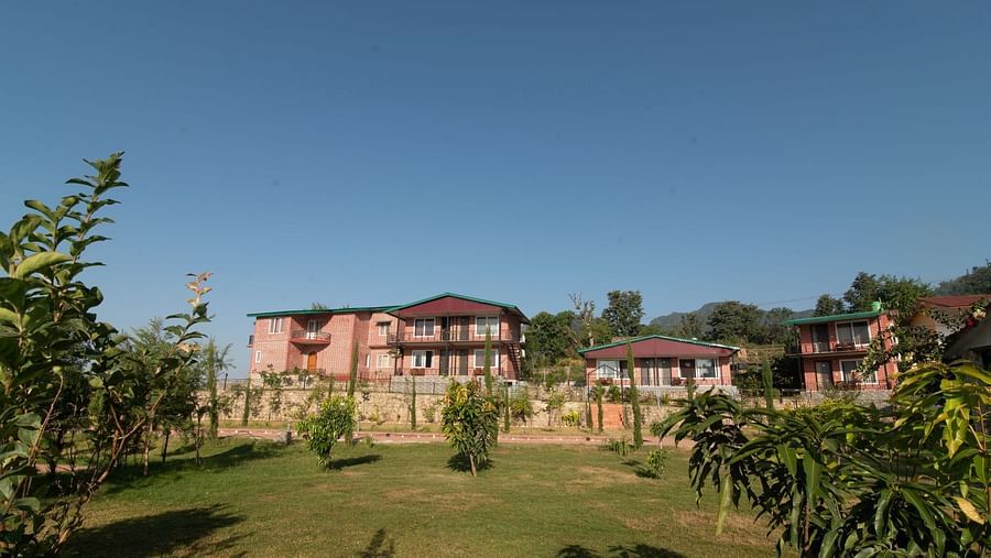 Facade of Neer ganga Resorts with a lush green lawn in the front