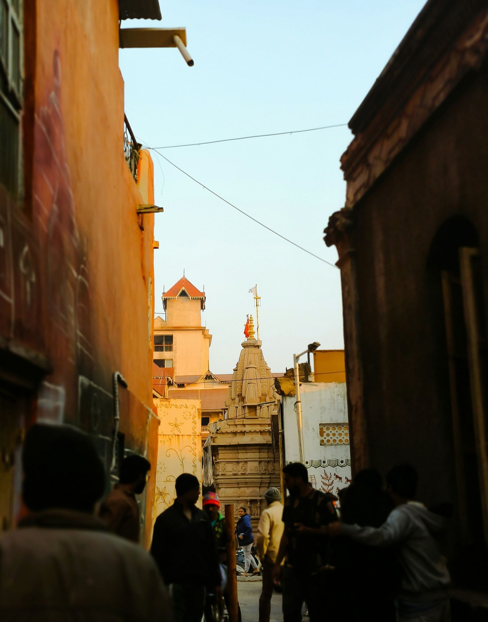 A dimly lit street with the silhouette of people walking in front.