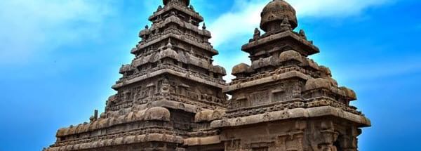 A temple complex near Hotel Mamallaa Heritage, Mahabalipuram, showcasing twin shrines with carvings and multiple stone sculptures.