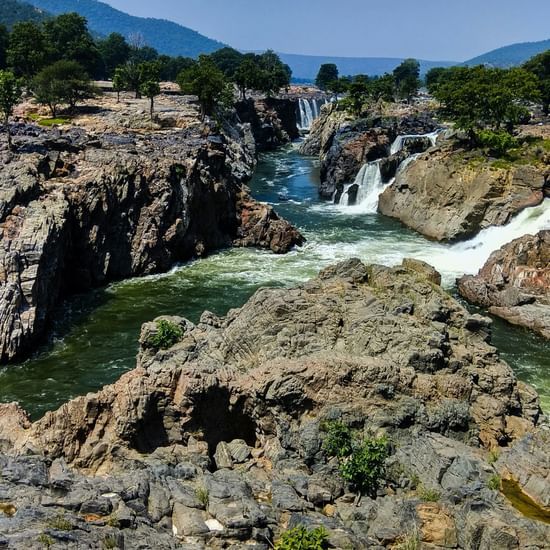 Majestic waterfalls flowing between rocky cliffs surrounded by greenery.