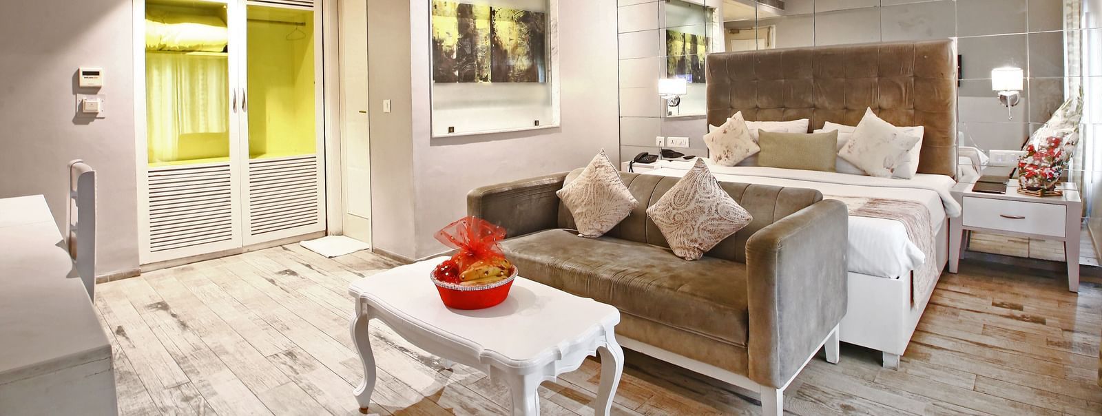 Elegant room with a large bed and a sofa in front, table, chairs, and TV unit at Hotel Emerald, Chandigarh
