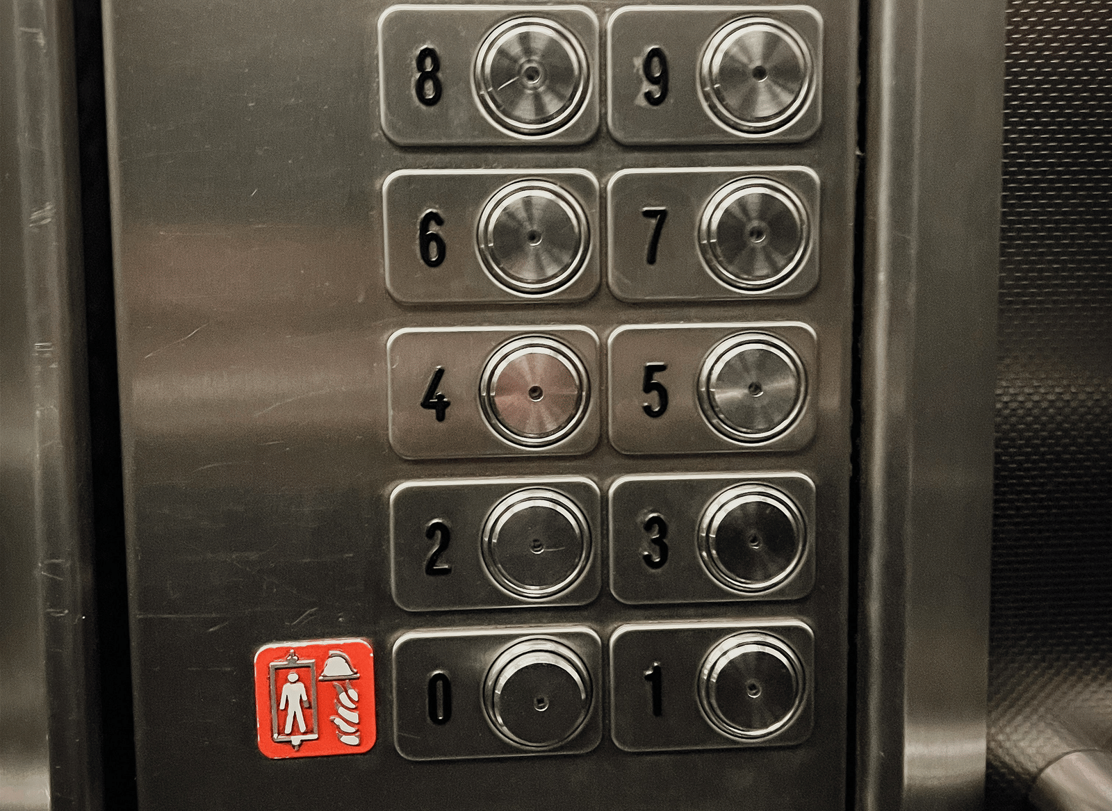 A close-up of a stainless steel elevator panel showing multiple round buttons for floor selection