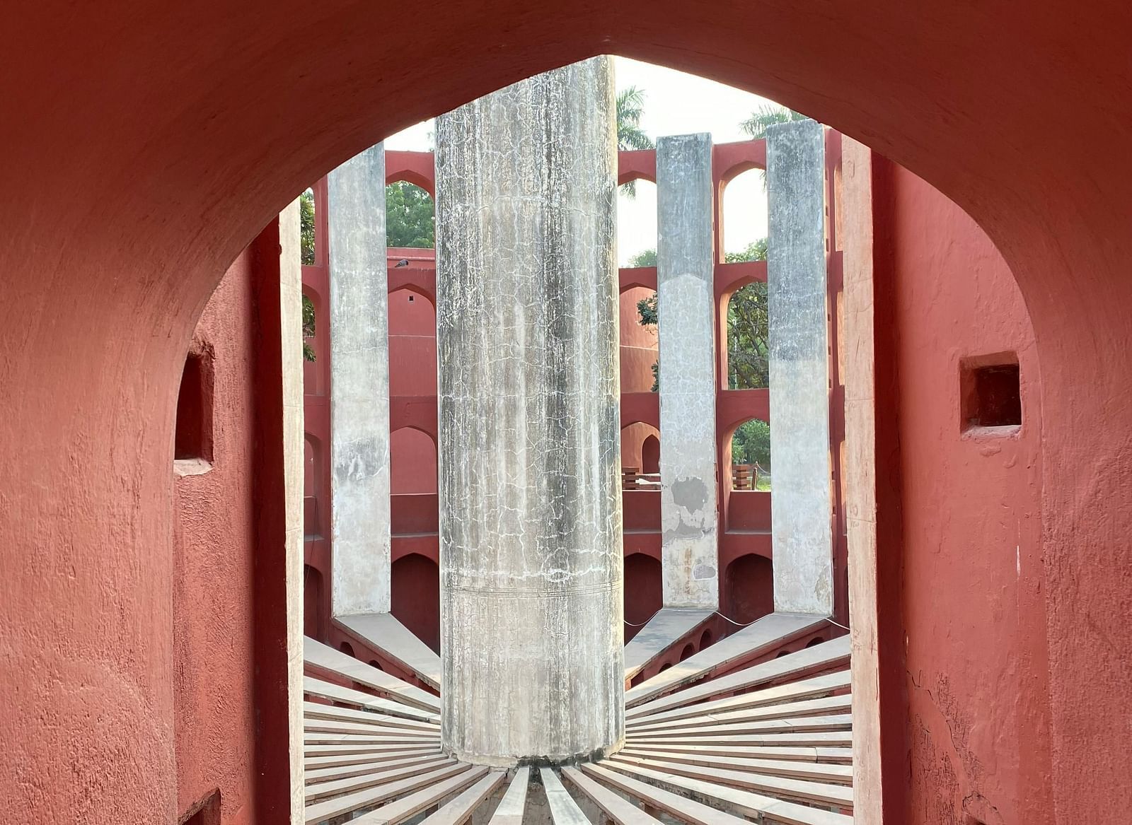 Architectural view through an archway at Jantar Mantar, showing a large sundial structure.
