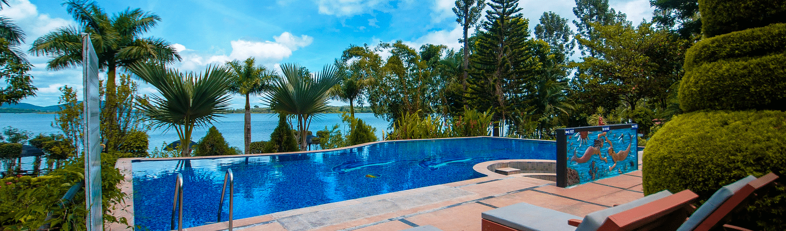 A swimming pool with sun loungers on the side at Coorg Jungle Camp Backwater Resort, Kushalnagar.