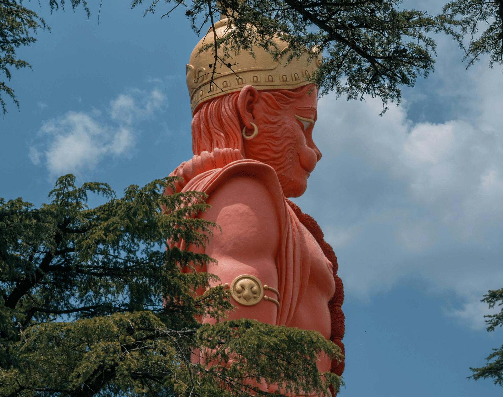 A tall Hanuman statue surrounded by trees.