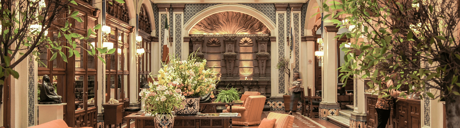 A lobby area featuring neatly arranged cushioned sofas, adorned with an abundance of decorative plants