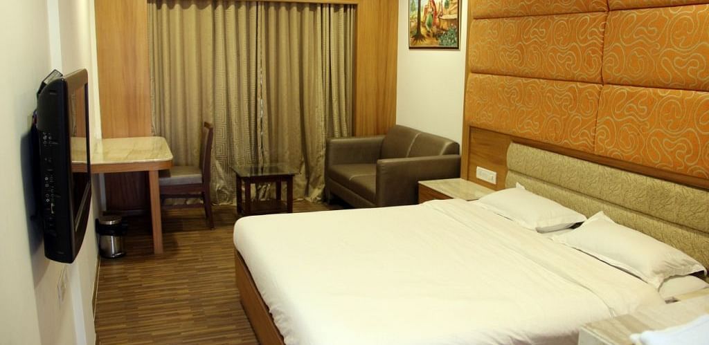 Well-lit hotel room with large bed, work desk, and TV