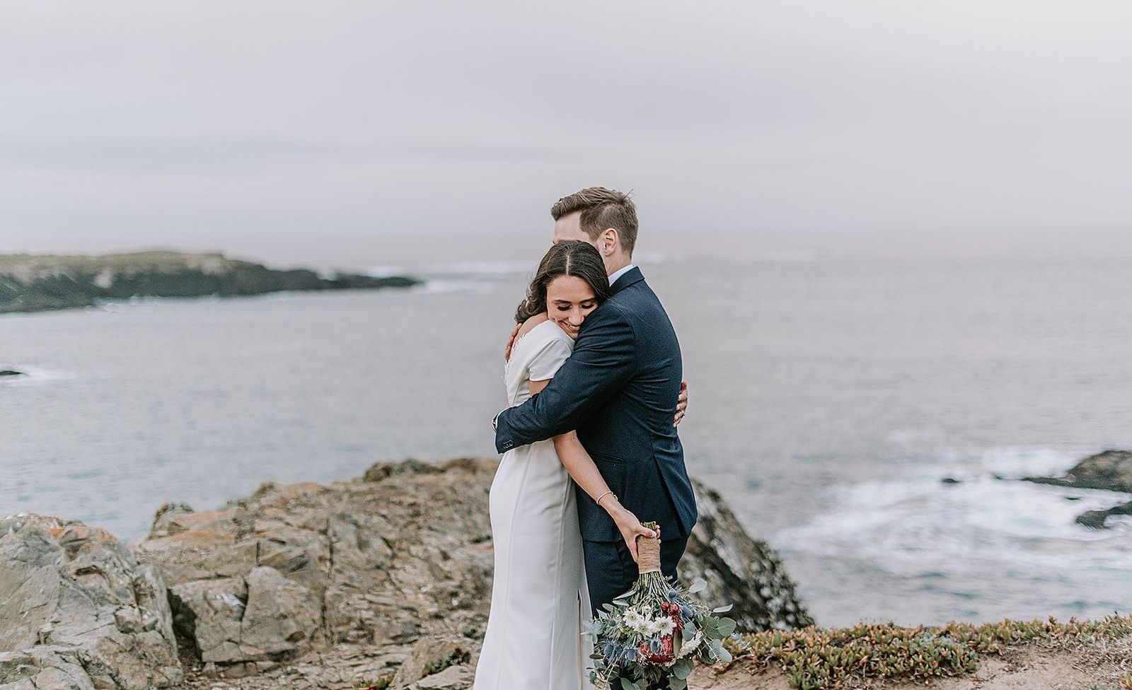 A couple embracing each other on a cliff by the ocean