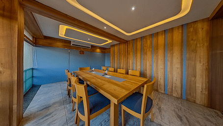Elegant conference room at Lords Eco Inn Dahej with wooden paneling, blue upholstered chairs, and modern lighting for corporate meetings