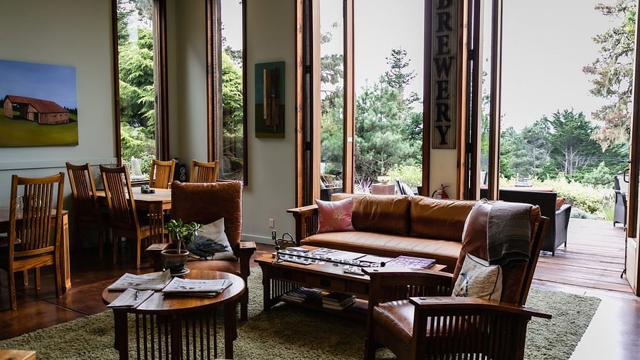Bright and open lounge space with wooden chairs, a fireplace, and large glass doors overlooking nature - Brewery Gulch Inn & Spa
