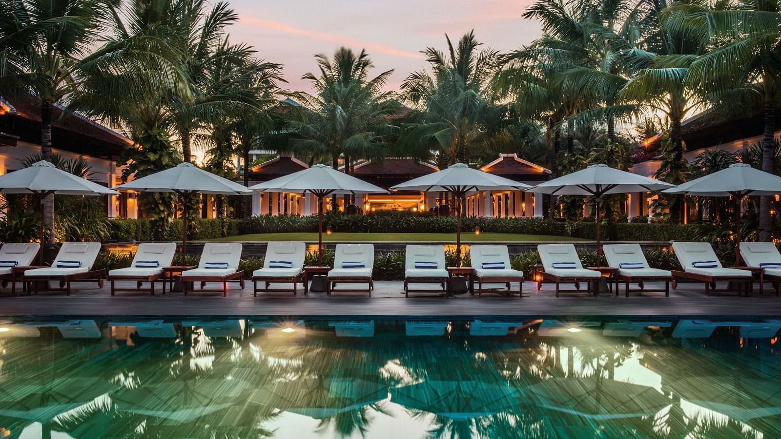 beach chairs and umbrellas in front of a pool
