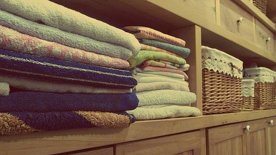 Image of clothes folded and placed in shelves next to a laundry bucket