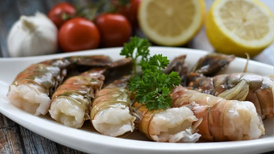 A plate of cooked shrimp garnished with parsley, alongside lemons, garlic, and tomatoes | Altamont Court, Jamaica