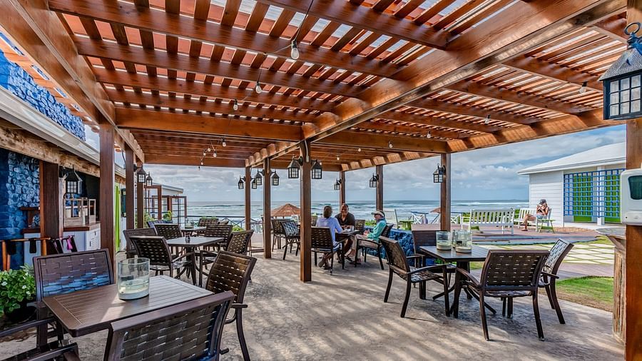 Outdoor dining space with wooden roof and tables | Abaco Inn
