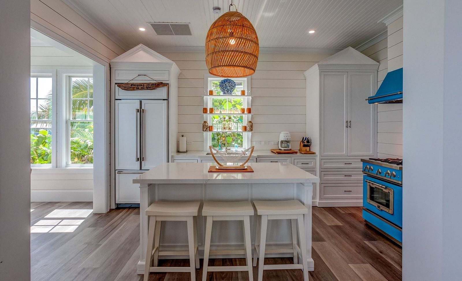 Kitchen and dining area featuring a white island, blue stove, and woven pendant light | Abaco Inn