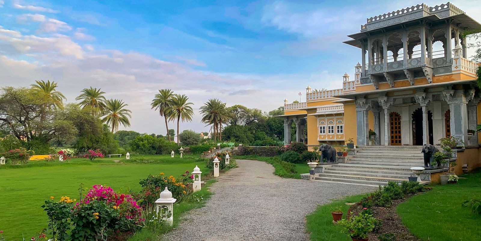 a tranquil Facade image of Dev Shree, Deogarh with a beautiful green lawn in the foreground
