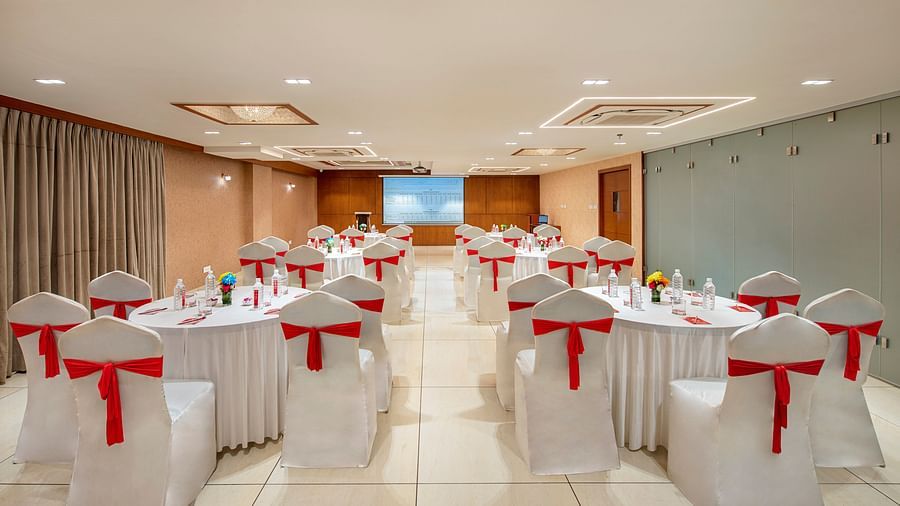 A banquet hall with round tables elegantly set for a formal occasion, likely a wedding or reception - SK Lords Inn Ahmedabad