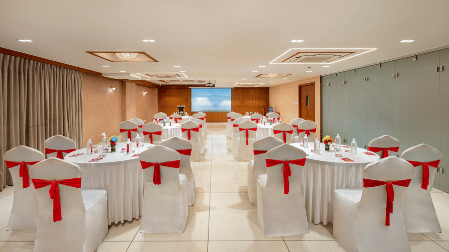 A banquet hall with round tables elegantly set for a formal occasion, likely a wedding or reception - SK Lords Inn Ahmedabad