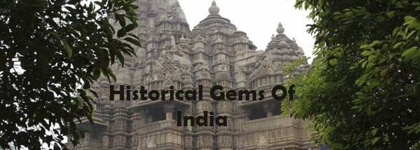 A stone temple structure with 3 towers and carvings,surrounded by trees with text 'Historical Gems Of India' in the image.