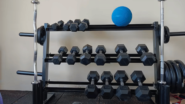 A rack with dumbbells and weights stacked as per weight categories at the gym of Leroy Grand, Yeshwanthpur. 