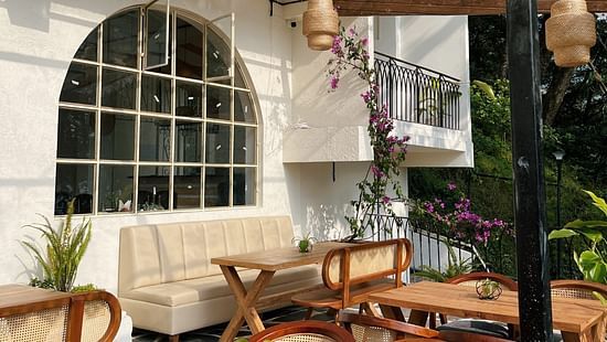 Outdoor dining area with wooden tables, wicker chairs, and pendant lights. - VITS Select Kunjham, Gangtok