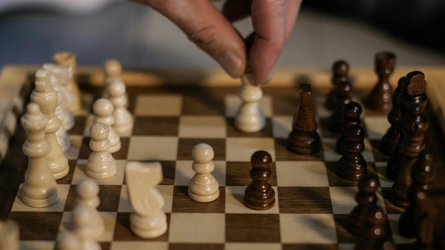 image featuring a wooden chess board with two people playing chess on it