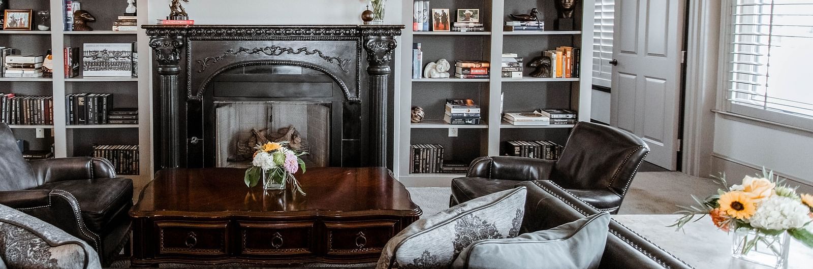  A stylish living room with large bookshelves, a fireplace, and plush seating, creating a warm and inviting atmosphere - The Grand Hotel & Ballroom, McKinney