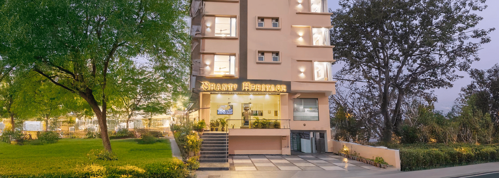 Facade of Perfectstayz Premium Shanti Heritage, Haridwar with trees surrounding the hotel.