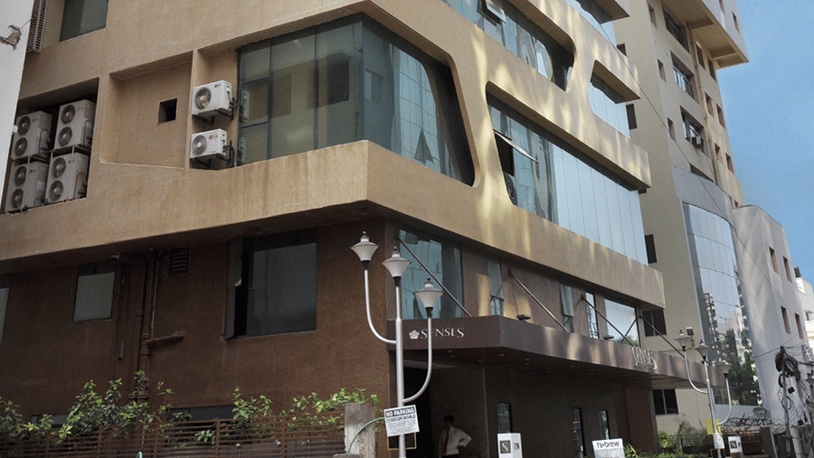 Full view exterior shot of Senses Hotel with a bright blue sky with clouds in the background.
